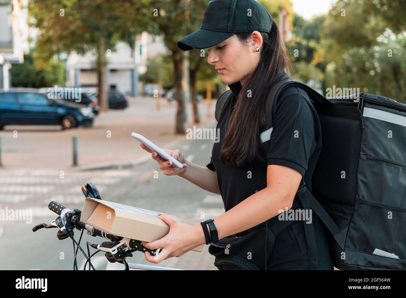 Jeune femme living scanner le paquet avec un smartphone Banque D'Images
