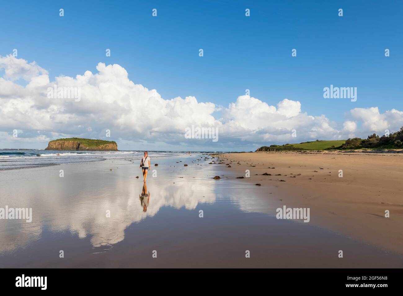 Femelle touriste marchant le long de la plage de Minnamurra avec Stack Island en arrière-plan Banque D'Images