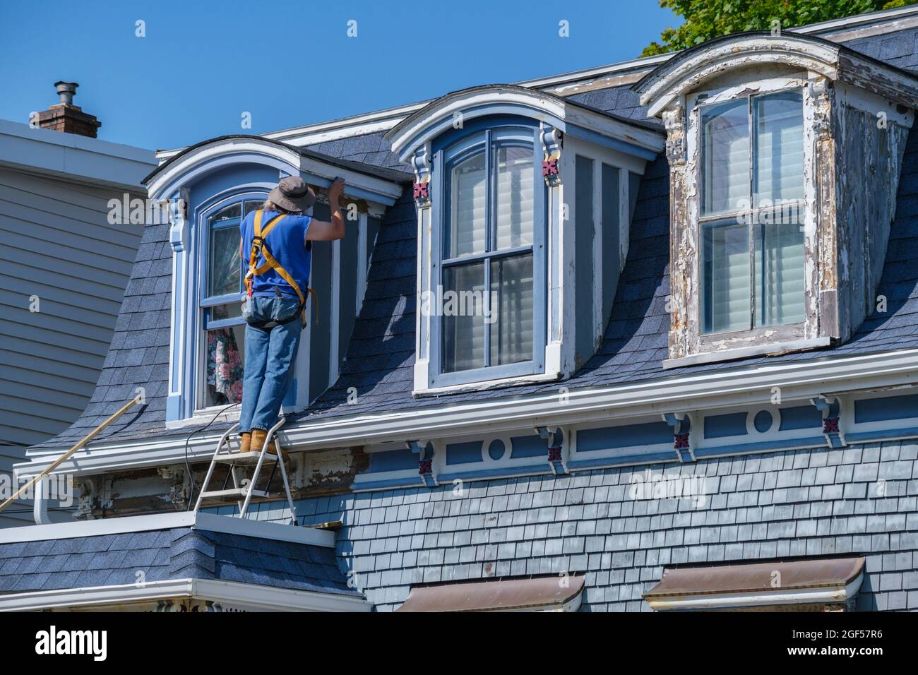 Dartmouth, Canada - 10 août 2021 : peinture abrasive des travailleurs sur le mur d'une vieille maison. Banque D'Images