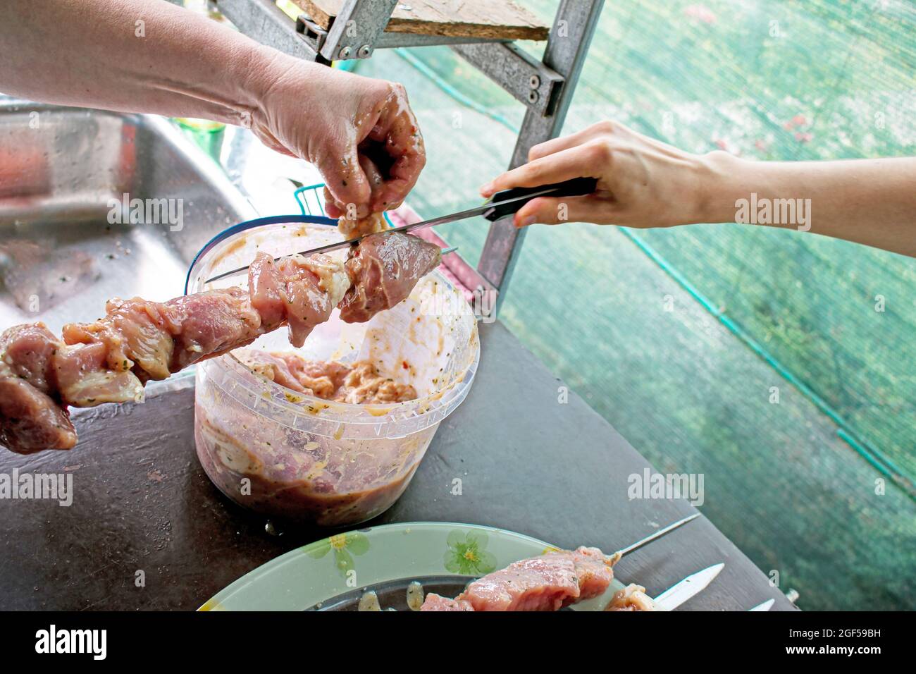 Une femme s'accroche à de la viande juteuse sur une brochette. Barbecue de cuisine dans la nature Banque D'Images