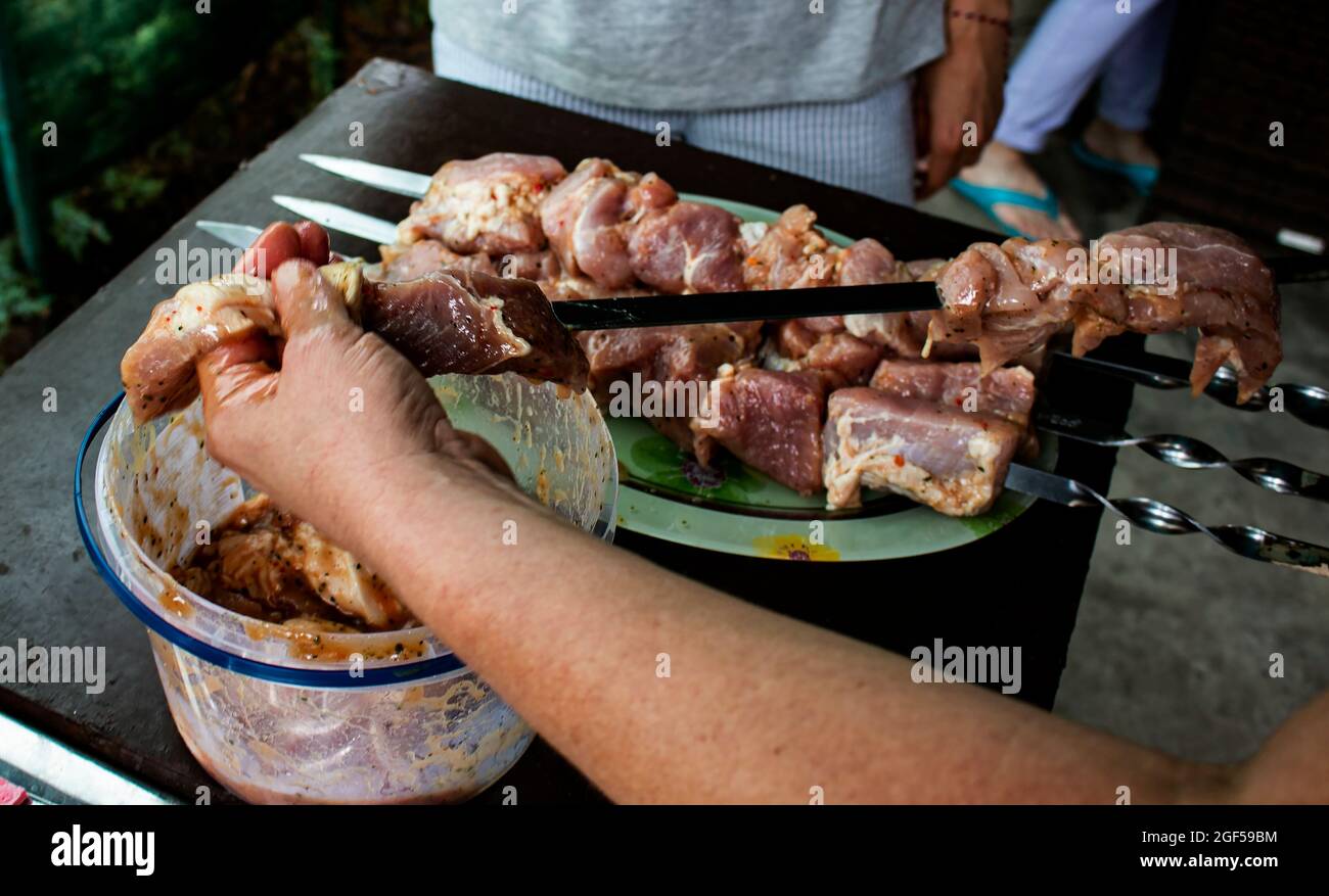 Une femme s'accroche à de la viande juteuse sur une brochette. Barbecue de cuisine dans la nature Banque D'Images