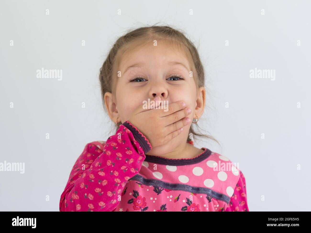 Portrait d'un drôle d'enfant caucasien de trois ans mettant sa main sur la bouche pour garder un silence et de ne pas rire dans un fort Banque D'Images