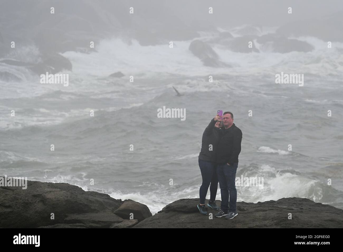 Maine, États-Unis. 22 août 2021. Un couple se photographie avec des vagues écrasant contre des rochers à l'extérieur du phare de Nubble. (Photo par Aimee Dilger/ SOPA Images/Sipa USA) crédit: SIPA USA/Alay Live News Banque D'Images