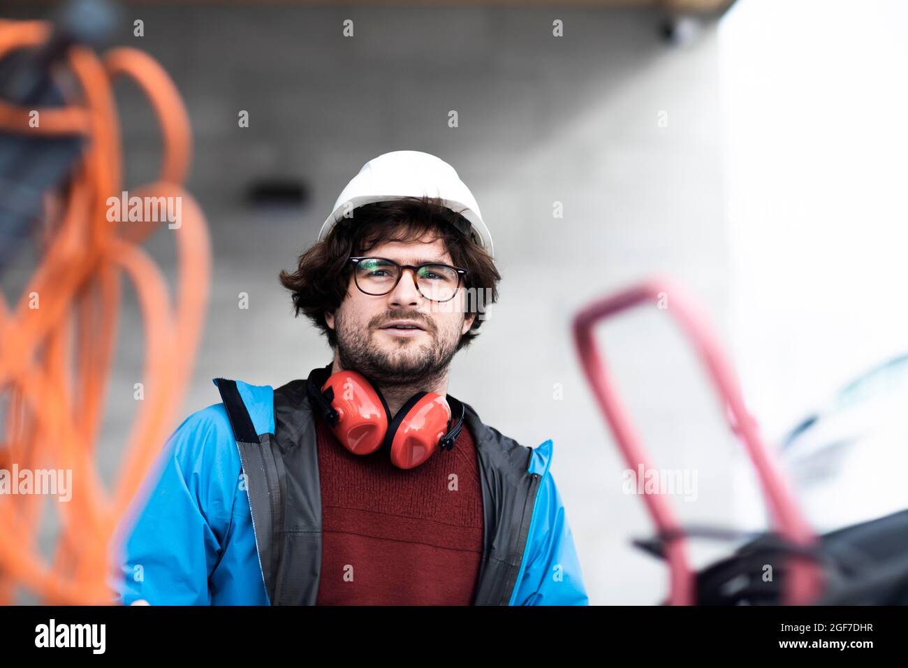 Un jeune ingénieur avec casque et contrôles de protection auditive à l'extérieur du lieu de travail, Fribourg, Bade-Wurtemberg, Allemagne Banque D'Images