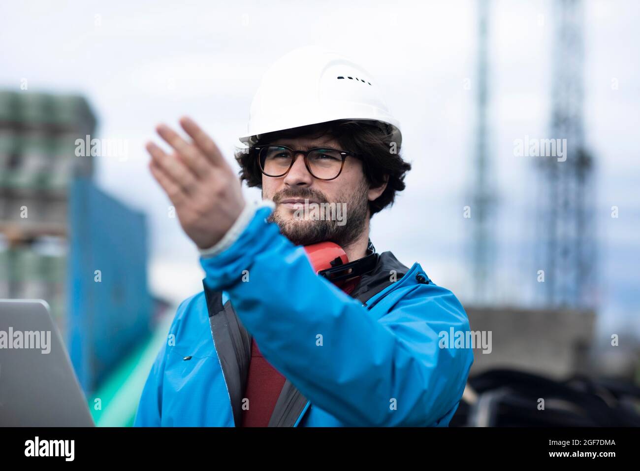 Jeune ingénieur portant un casque et une protection auditive sur un lieu de travail extérieur avec un ordinateur portable, Fribourg, Bade-Wurtemberg, Allemagne Banque D'Images