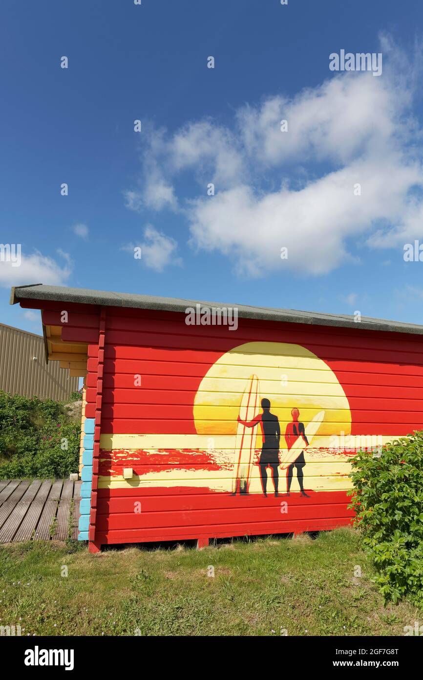 Hutte rouge avec graffito, deux surfeurs devant le soleil couchant, Sylt, îles de la Frise du Nord, Schleswig-Holstein, Allemagne Banque D'Images