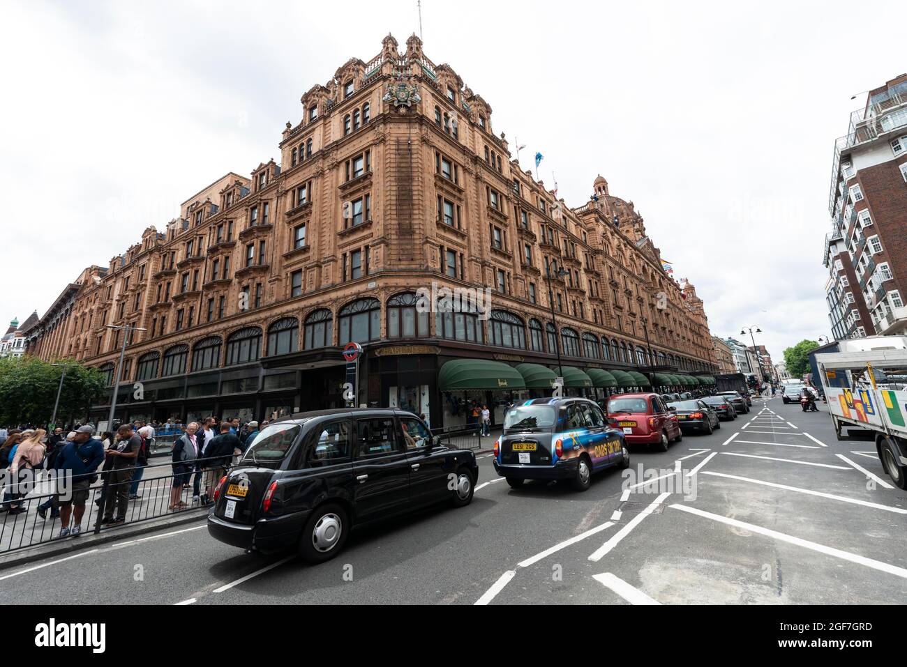 Taxis alignés dans la rue devant les grands magasins de luxe, Harrods, Londres, Angleterre, Royaume-Uni Banque D'Images