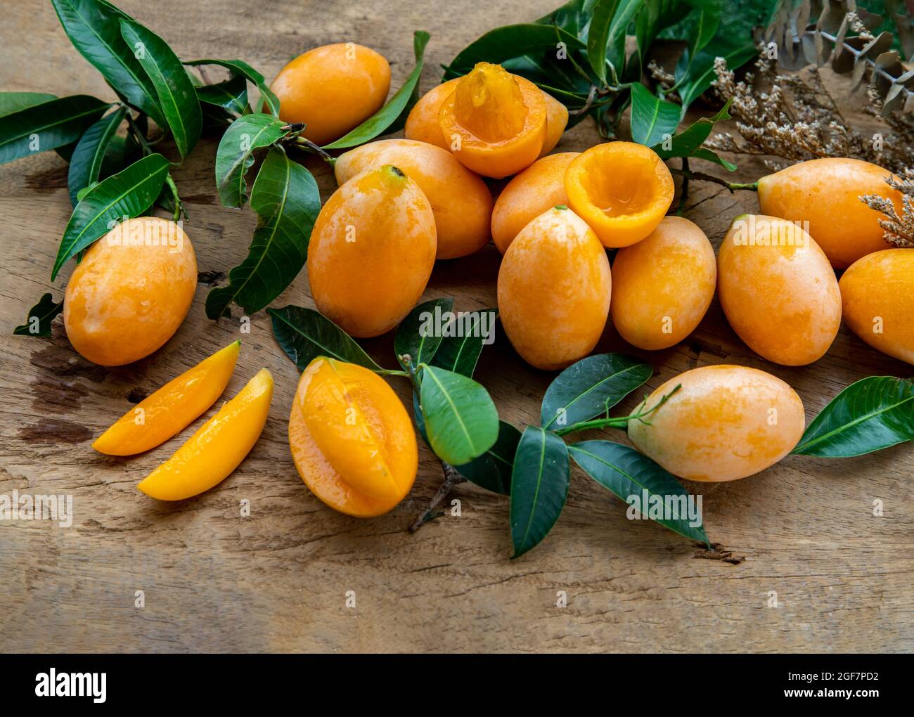 Prunes mariales fraîches jaune doux ou mayonnaise avec feuille verte sur fond de bois. Concept de fruits exotiques tropicaux, foyer sélectif. Banque D'Images