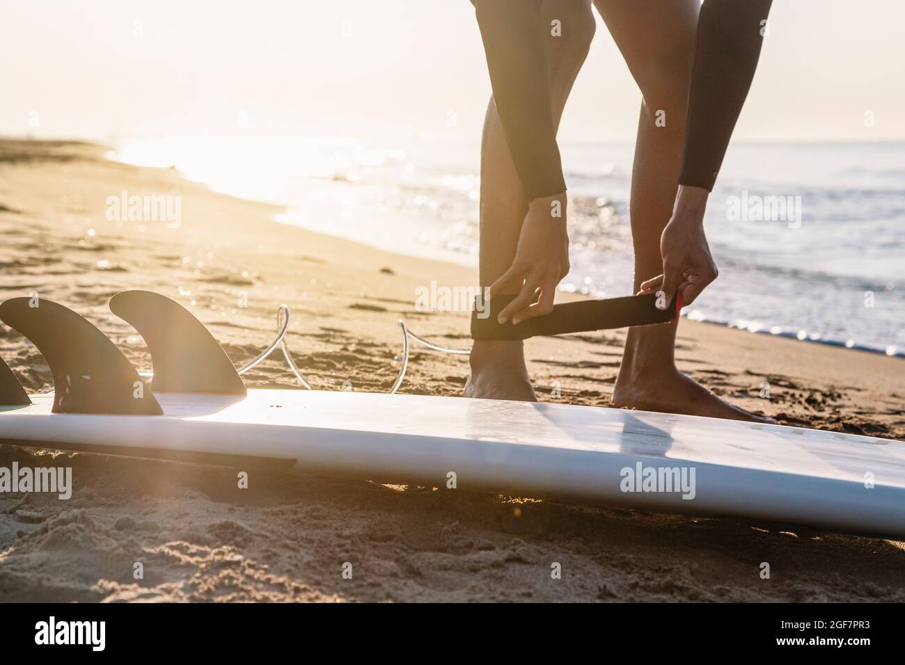 Surfeur se préparant à surfer sur la plage au lever du soleil. Banque D'Images