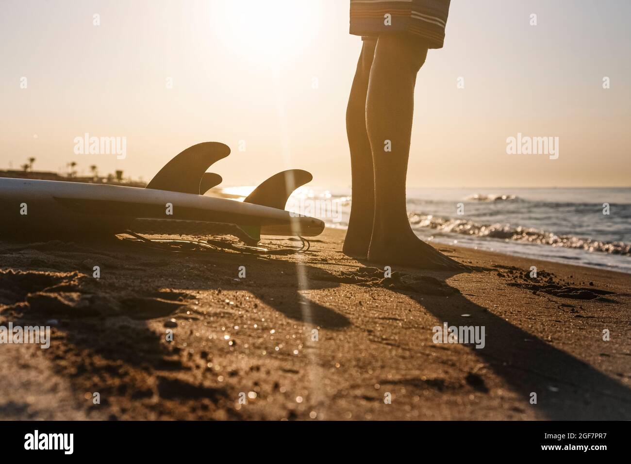 Surfeur se préparant à surfer sur la plage au lever du soleil. Banque D'Images