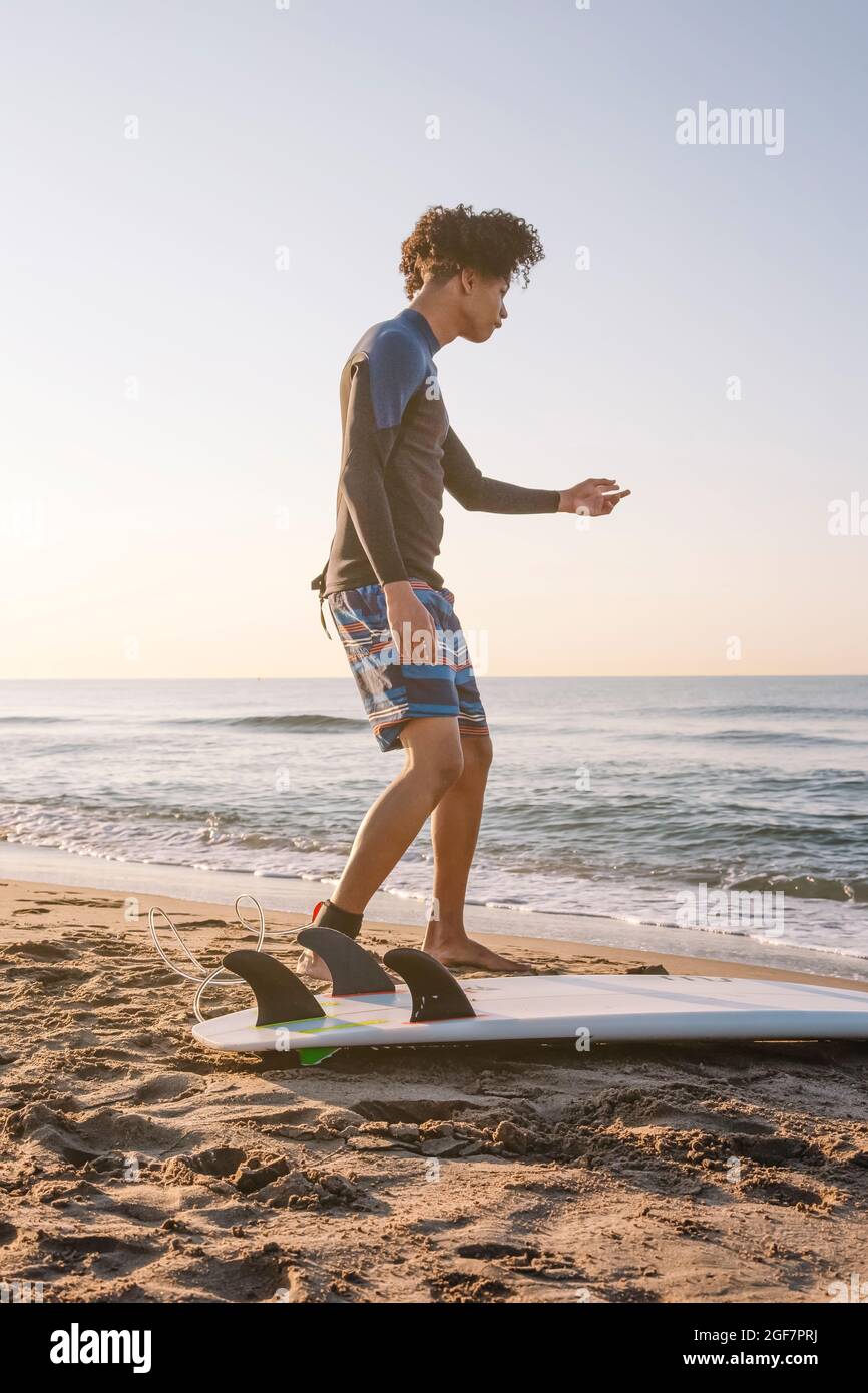 Surfeur se préparant à surfer sur la plage au lever du soleil. Banque D'Images