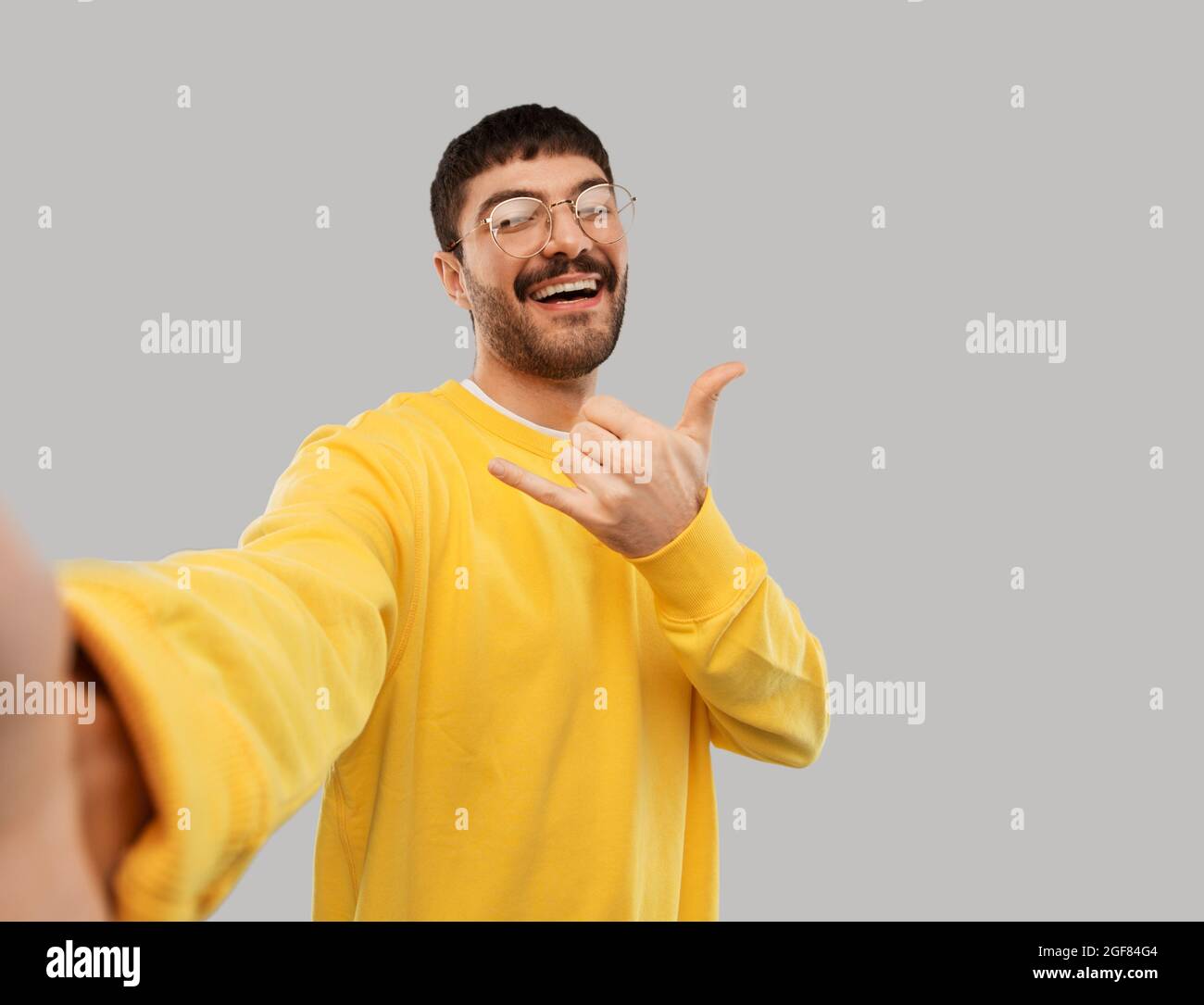 joyeux jeune homme en chandail jaune faisant le selfie Banque D'Images