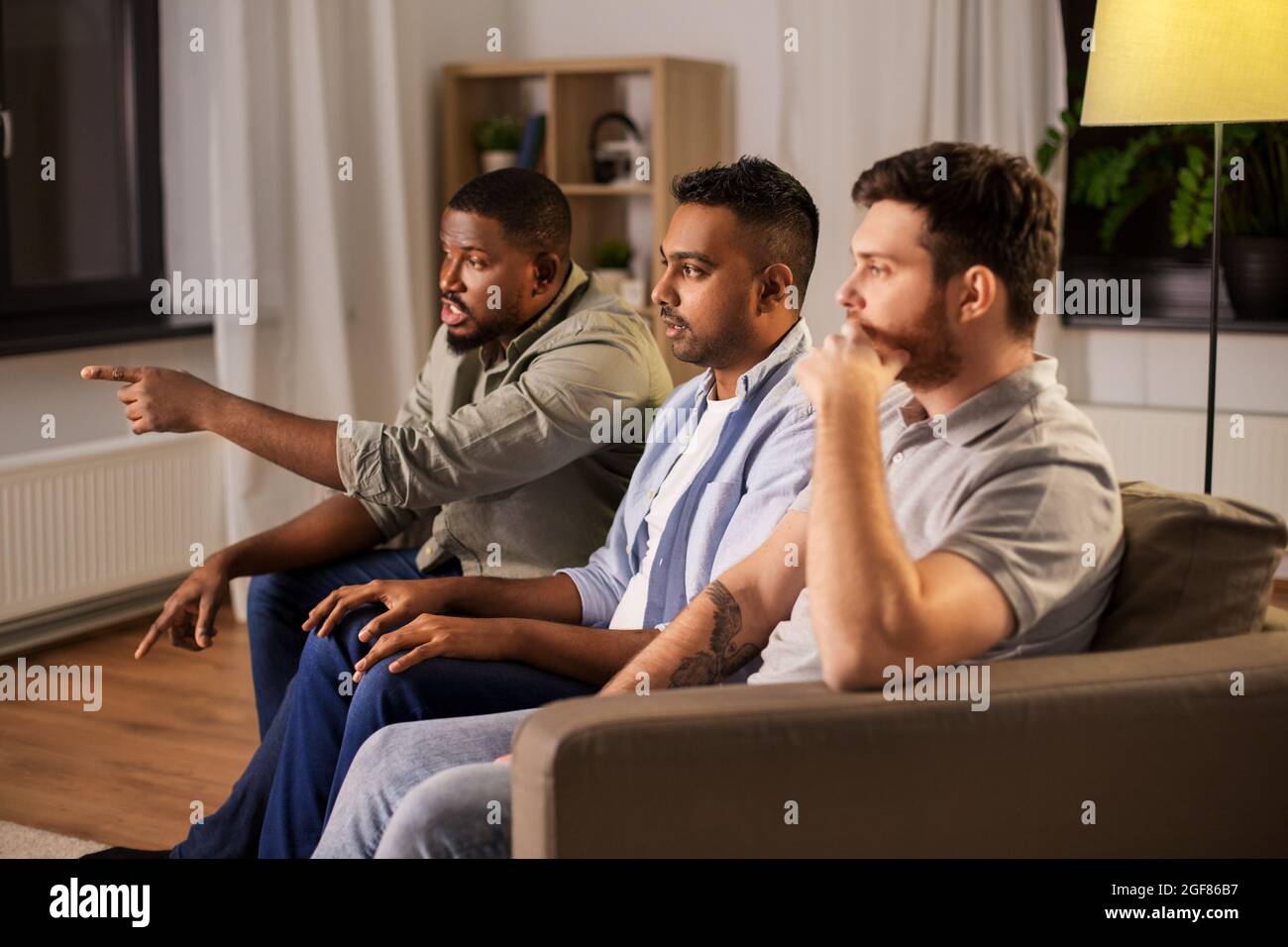 amis de sexe masculin regardant la télévision et parlant à la maison Banque D'Images