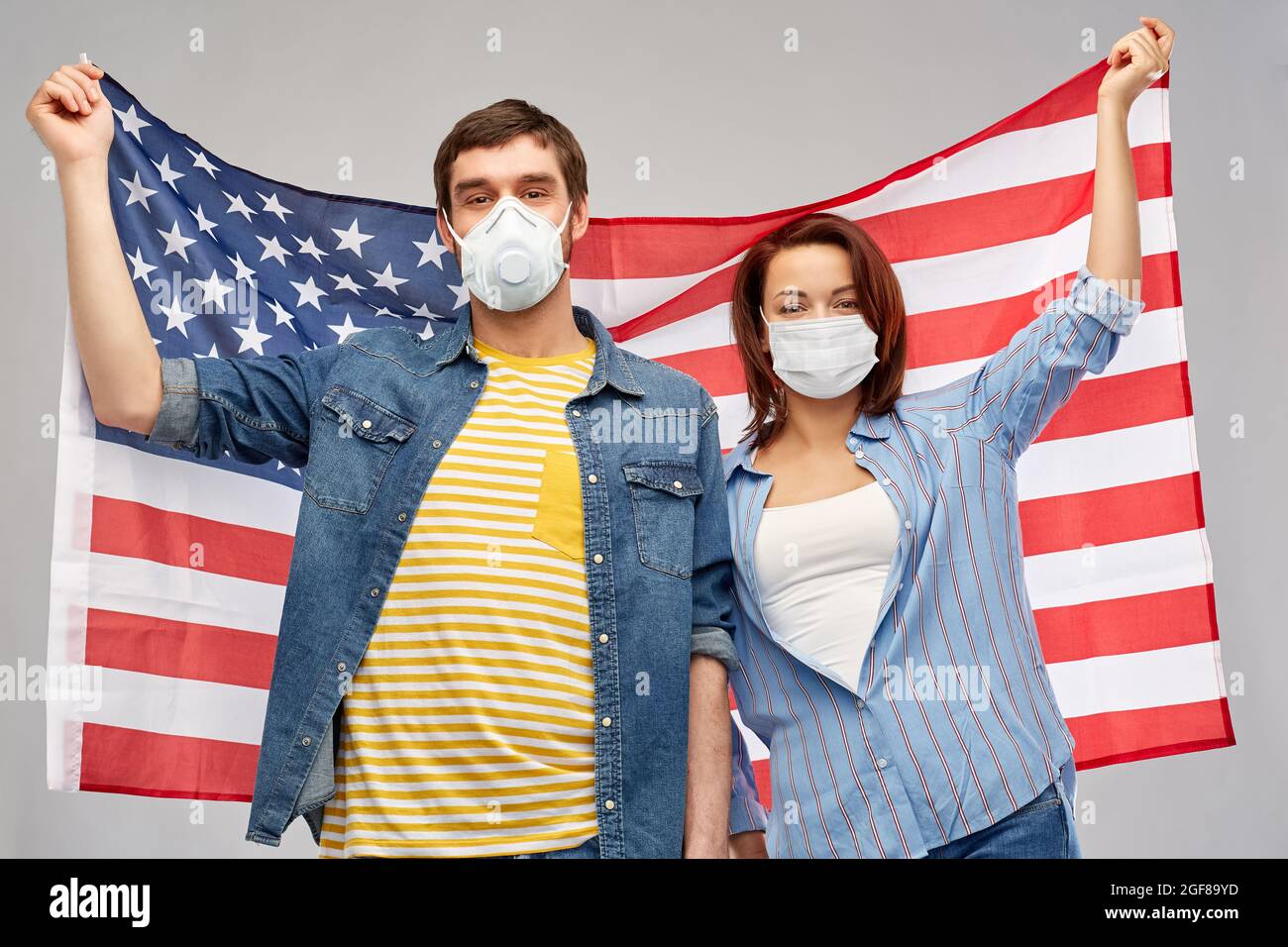 couple dans les masques de visage tenant le drapeau de l'amérique Banque D'Images