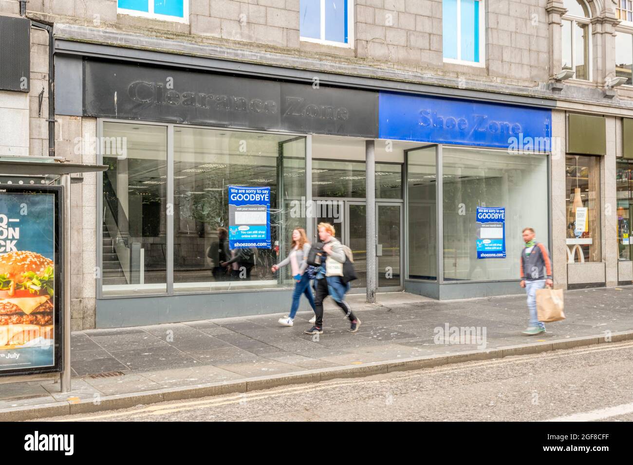 Les gens (mouvement flou) se prometent devant les magasins vides de la zone des chaussures et de la zone de liquidation à Union Street, Aberdeen. Banque D'Images