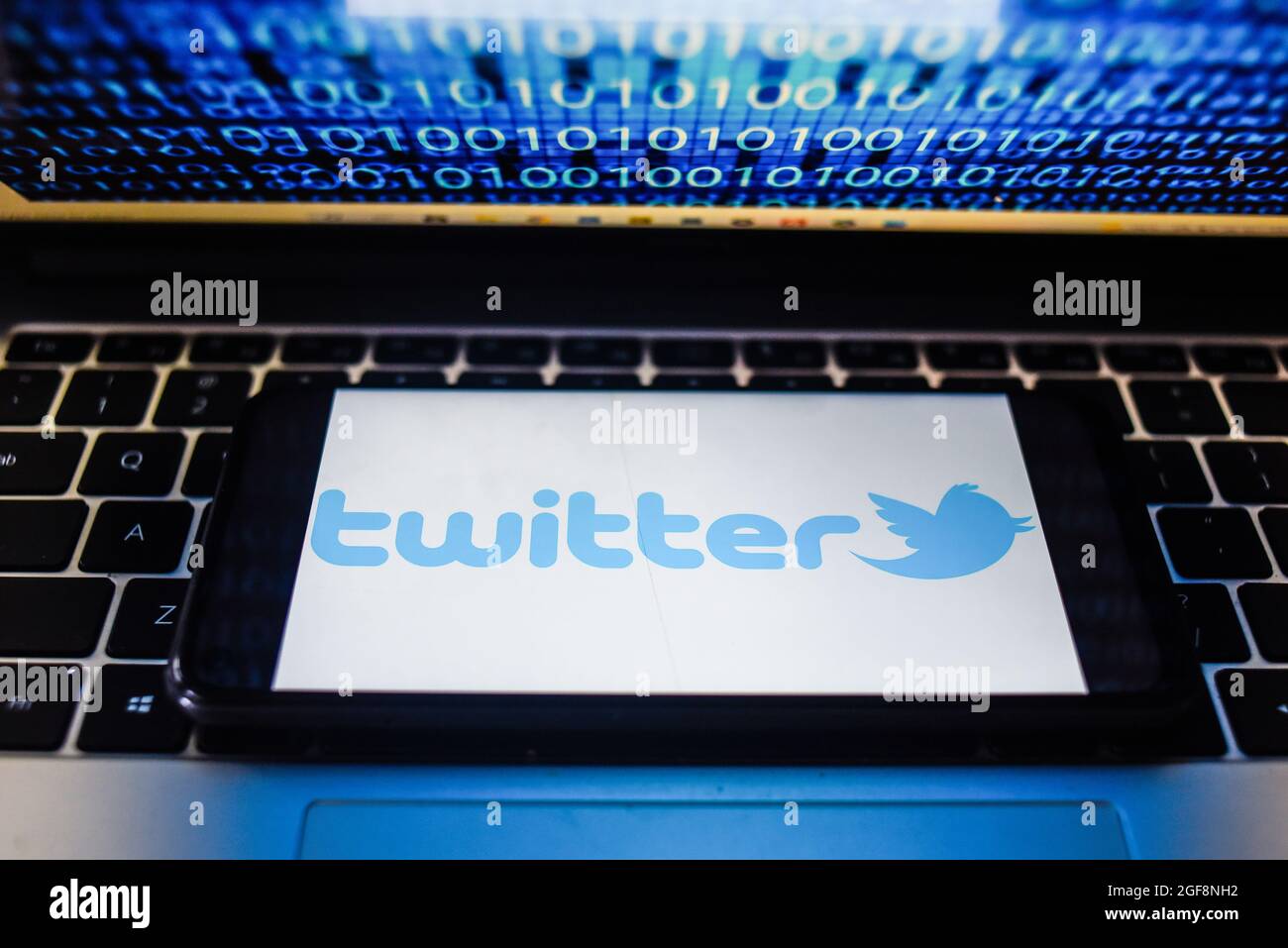 Portugal. 24 août 2021. Sur cette photo, un logo Twitter s'affiche sur un smartphone avec un code binaire sur l'écran d'un ordinateur portable. Crédit : SOPA Images Limited/Alamy Live News Banque D'Images