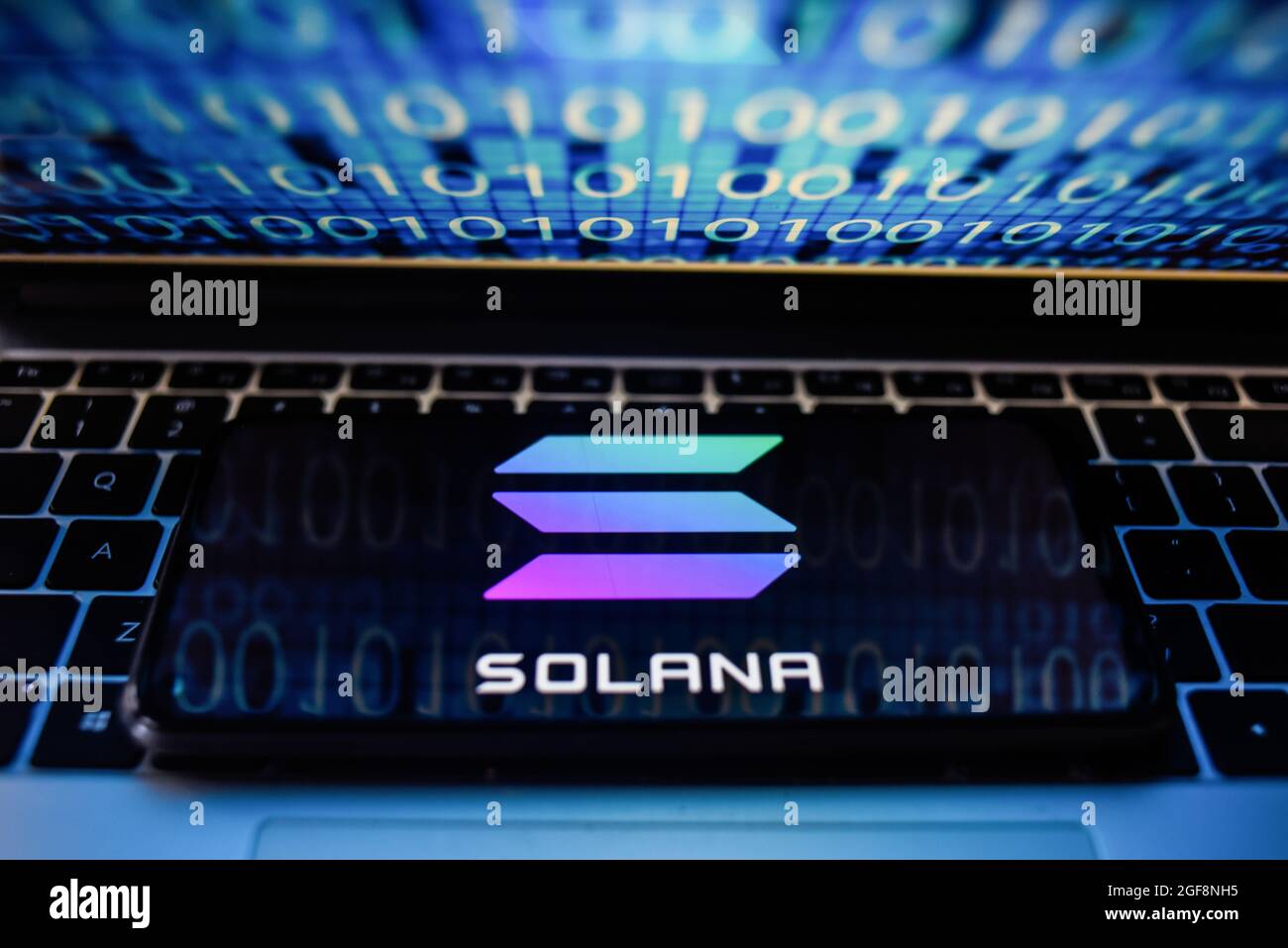 Portugal. 24 août 2021. Sur cette photo, un logo Solana s'affiche sur un smartphone avec un code binaire sur l'écran d'un ordinateur portable. Crédit : SOPA Images Limited/Alamy Live News Banque D'Images