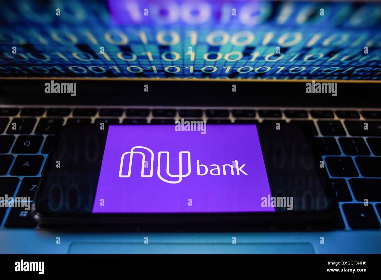 Portugal. 24 août 2021. Sur cette photo, un logo nu Bank s'affiche sur un smartphone avec un code binaire sur l'écran d'un ordinateur portable. Crédit : SOPA Images Limited/Alamy Live News Banque D'Images