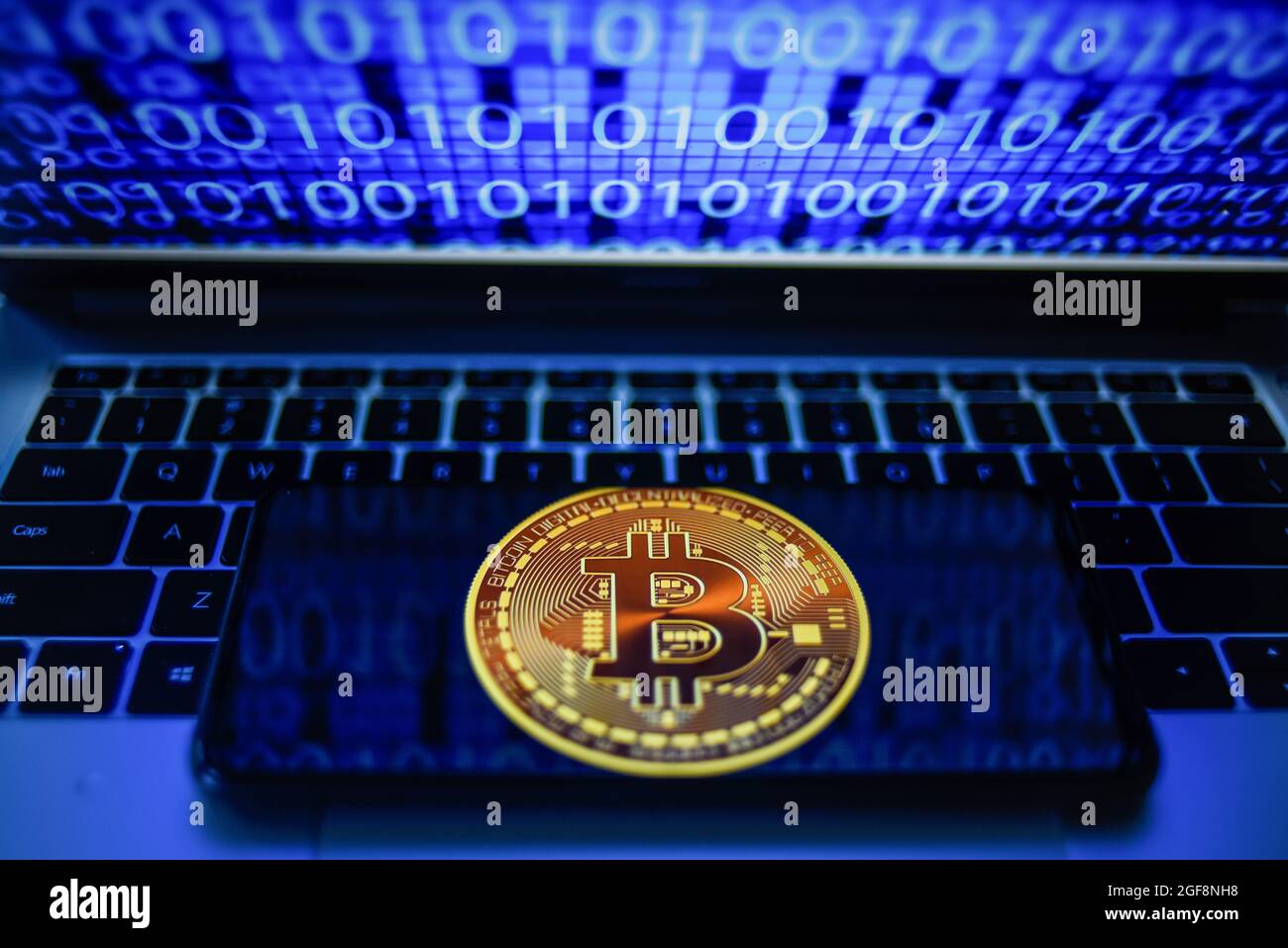 Portugal. 24 août 2021. Sur cette photo, un logo Bitcoin s'affiche sur un smartphone avec du code binaire sur l'écran d'un ordinateur portable. Crédit : SOPA Images Limited/Alamy Live News Banque D'Images
