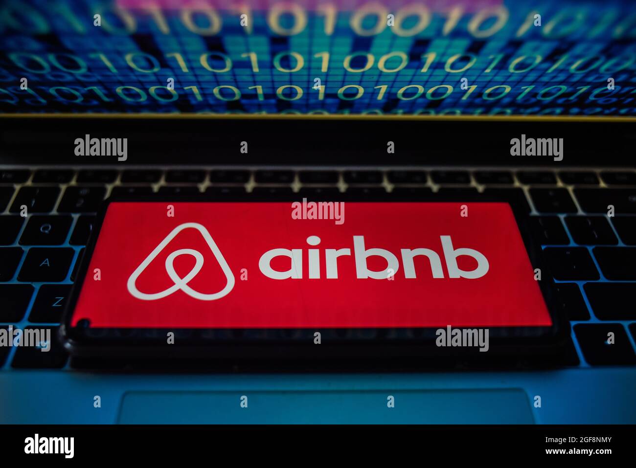 Portugal. 24 août 2021. Sur cette photo, un logo Airbnb apparaît sur un smartphone avec du code binaire sur l'écran d'un ordinateur portable. Crédit : SOPA Images Limited/Alamy Live News Banque D'Images