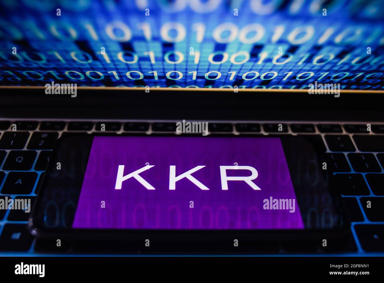 Portugal. 24 août 2021. Sur cette photo, un logo KKR s'affiche sur un smartphone avec un code binaire sur l'écran d'un ordinateur portable. Crédit : SOPA Images Limited/Alamy Live News Banque D'Images