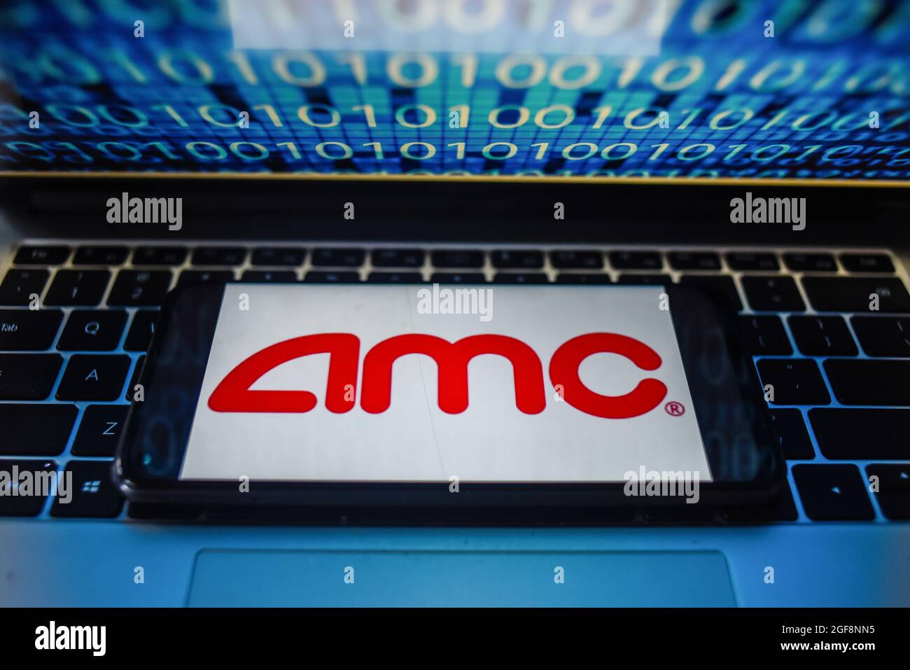 Portugal. 24 août 2021. Sur cette photo, un logo AMC s'affiche sur un smartphone avec un code binaire sur l'écran d'un ordinateur portable. Crédit : SOPA Images Limited/Alamy Live News Banque D'Images