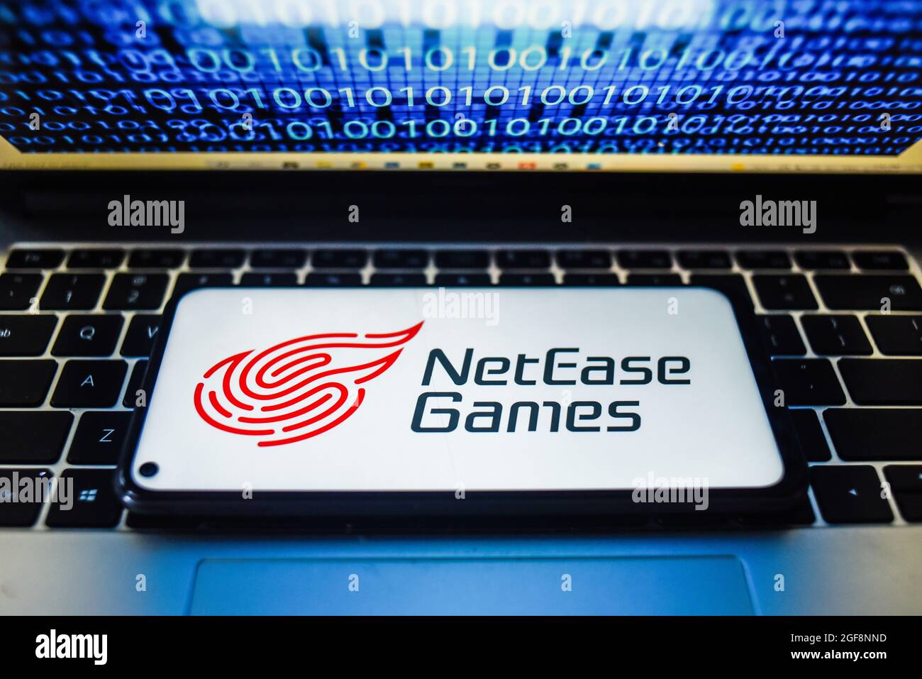 Portugal. 24 août 2021. Sur cette photo, un logo Net Ease Games apparaît sur un smartphone avec un code binaire sur l'écran d'un ordinateur portable. Crédit : SOPA Images Limited/Alamy Live News Banque D'Images