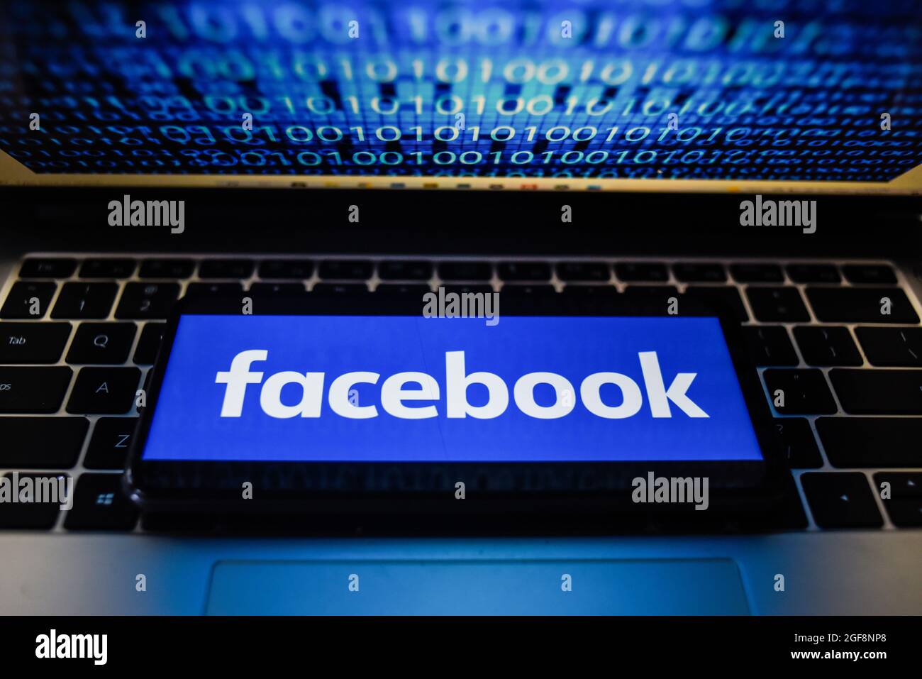 Portugal. 24 août 2021. Sur cette photo, un logo Facebook s'affiche sur un smartphone avec un code binaire sur l'écran d'un ordinateur portable. Crédit : SOPA Images Limited/Alamy Live News Banque D'Images