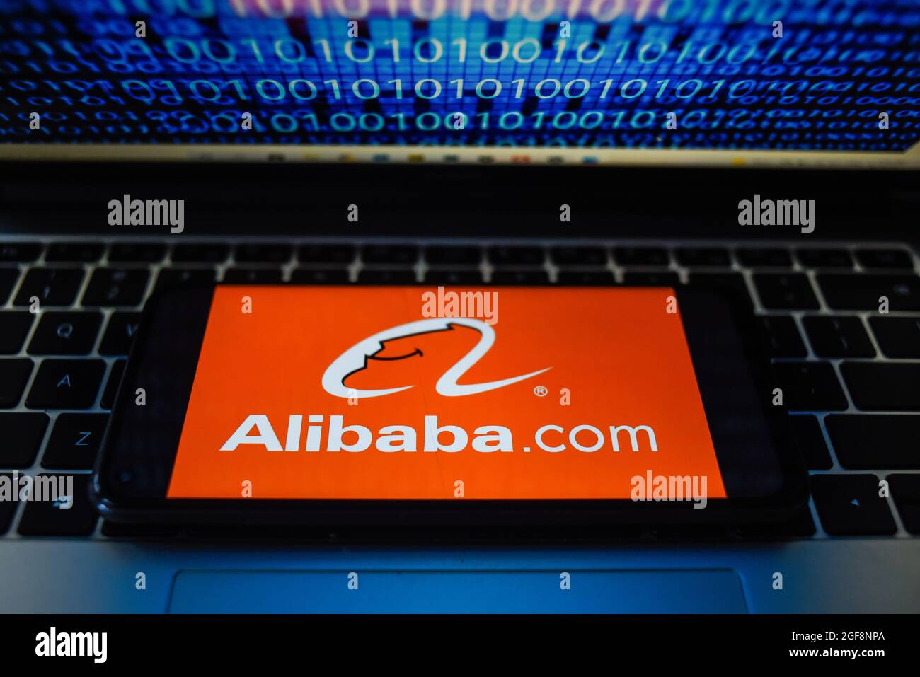Portugal. 24 août 2021. Sur cette photo, un logo Alibaba.com apparaît sur un smartphone avec un code binaire sur l'écran d'un ordinateur portable. Crédit : SOPA Images Limited/Alamy Live News Banque D'Images