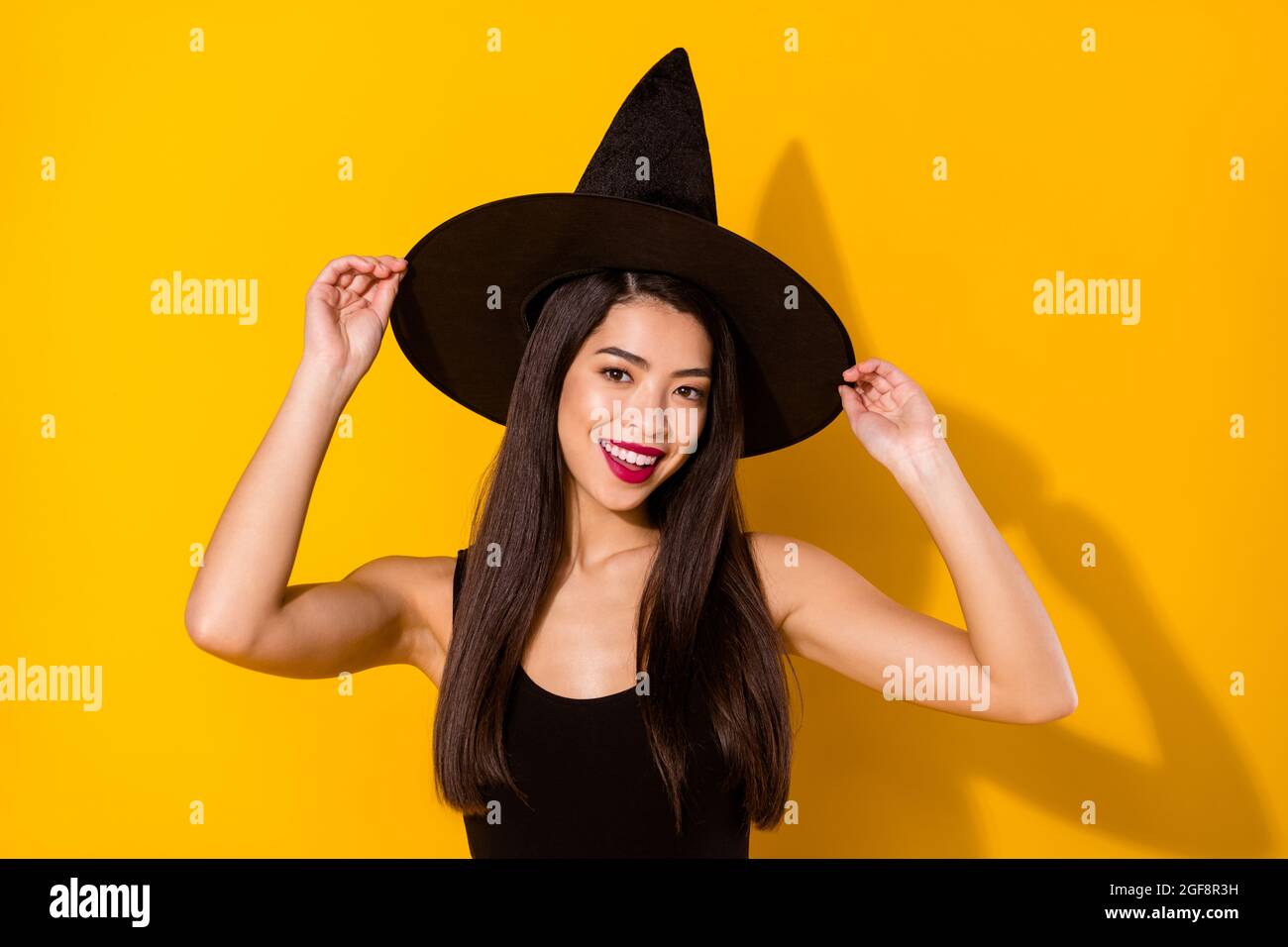 Photo de la belle dame de sorcière porter le chapeau de robe noir isolé sur  fond jaune Photo Stock - Alamy