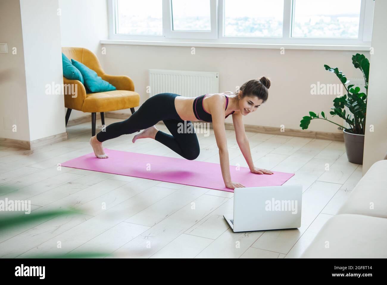 Femme vêtue de vêtements de sport à la maison à l'aide d'un ordinateur portable. Femme en ligne s'étirant et faisant l'exercice de forme physique de yoga. Sport, mode de vie sain. Soins du corps. Banque D'Images