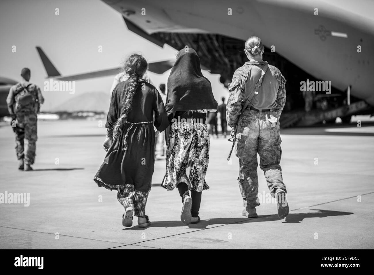 Une Marine avec la 24e unité expéditionnaire maritime (UMM) marche avec les enfants lors d'une évacuation à l'aéroport international Hamid Karzaï, Kaboul, Afghanistan, août 24. Les membres du service des États-Unis aident le ministère d'État à procéder à un retrait ordonné du personnel désigné en Afghanistan. (É.-U. Photo du corps marin par Sgt. Samuel Ruiz). Banque D'Images