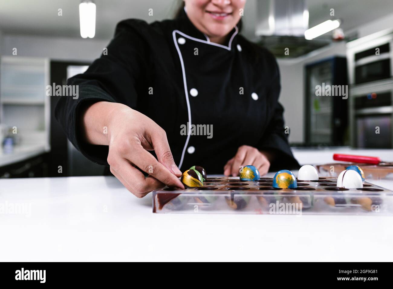 Main de la femme latine pâtissière vêtue de l'uniforme noir dans le processus de préparer de délicieux bonbons chocolats dans la cuisine au Mexique Amérique latine Banque D'Images