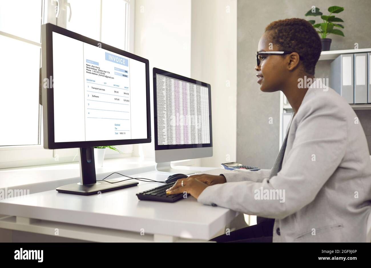 Femme comptable afro-américaine travaillant avec un logiciel pour les factures électroniques sur ordinateur. Banque D'Images
