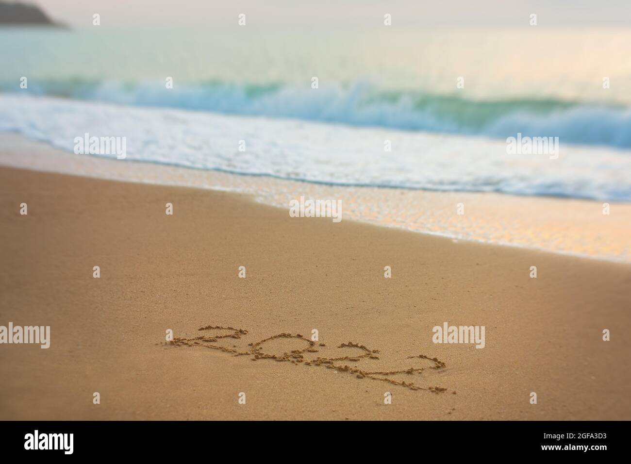 2022 bonne inscription du nouvel an plage de sable. Le texte écrit est écrit sur du sable jaune et est lavé par une vague. Le concept de changer l'année, Banque D'Images