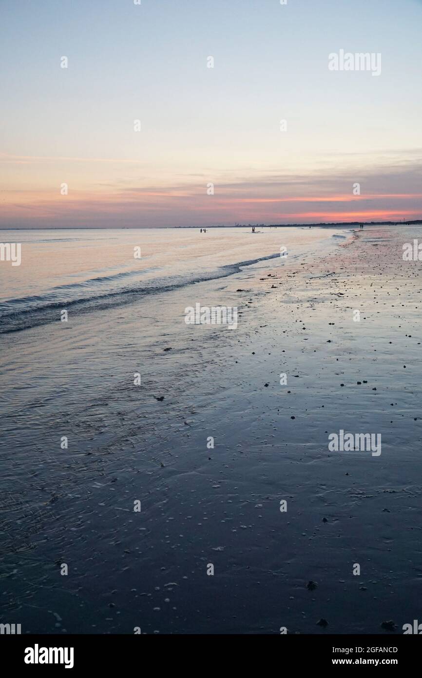 East Wittering, Royaume-Uni, 23 août 2021 : les vagues douces sur la plage de sable au crépuscule reflètent les bleus et les roses dans le ciel juste après le coucher du soleil. La mer est l'Engli Banque D'Images