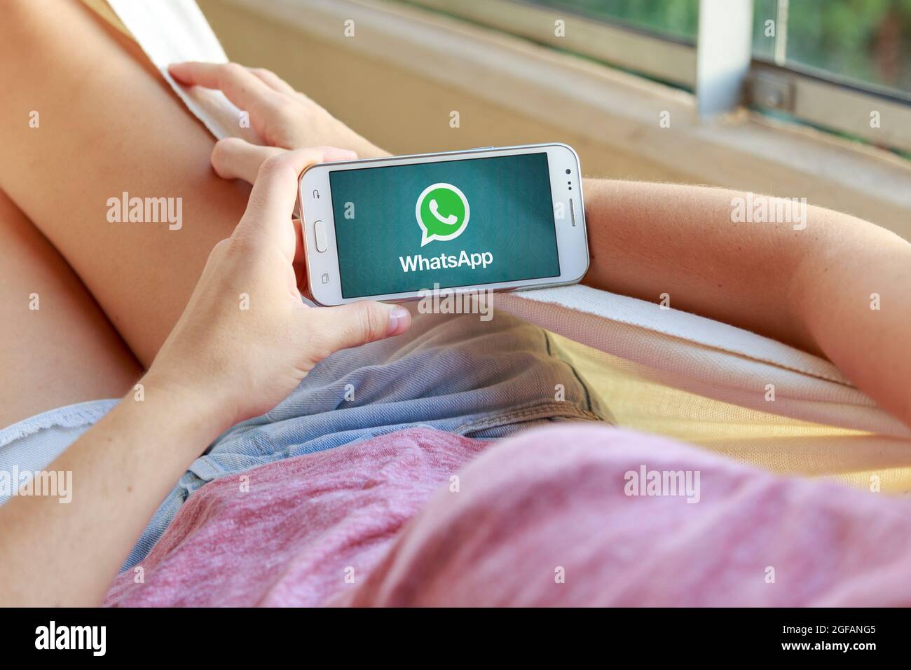 Femme dans un hamac avec un smartphone avec l'application whatsapp à l'écran. Jeune femme. Millénaire. Communications. Application. Banque D'Images