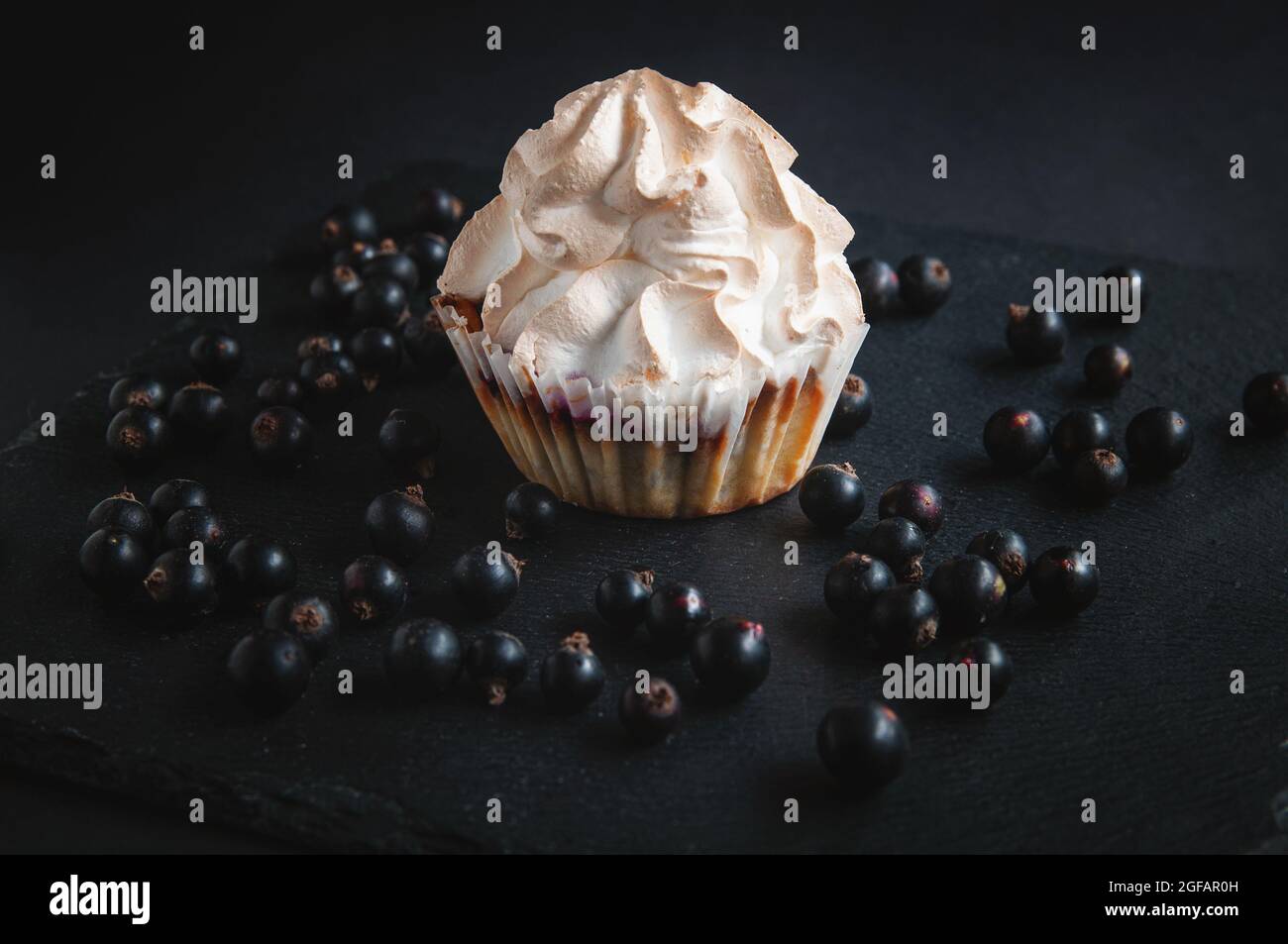 Muffin sur fond noir avec baies de cassis. Sur fond sombre, gâteaux aux fruits et baies et raisins de Corinthe sur une pierre noire servant bo Banque D'Images