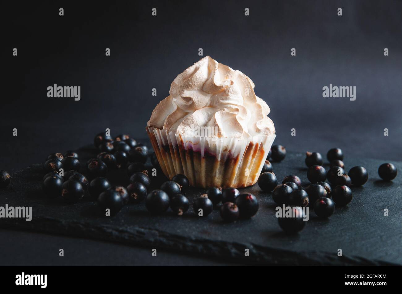 Muffin sur fond noir avec baies de cassis. Sur fond sombre, gâteaux aux fruits et baies et raisins de Corinthe sur une pierre noire servant bo Banque D'Images