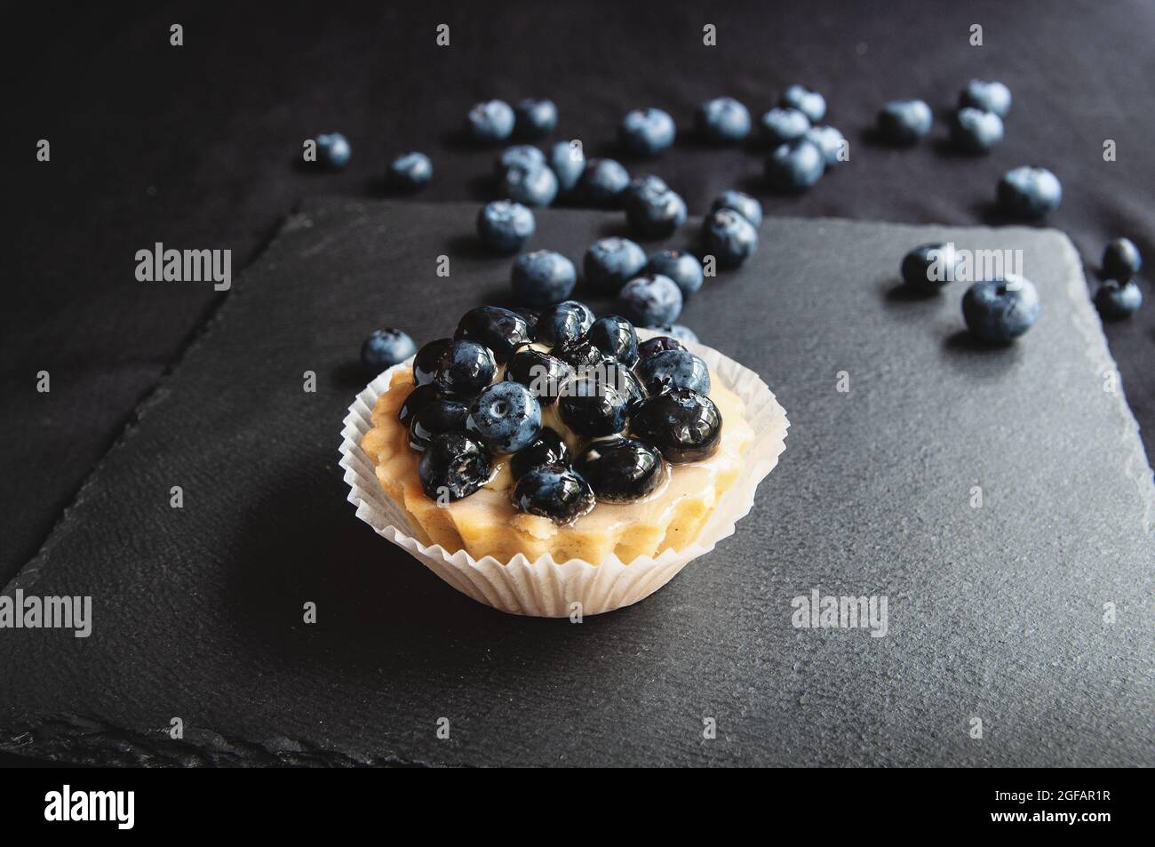 Tartes délicieuses et sucrées à base de crème et de myrtille. Tarte aux myrtilles sur fond sombre. Gâteau aux myrtilles sur une table de service noire parsemée Banque D'Images