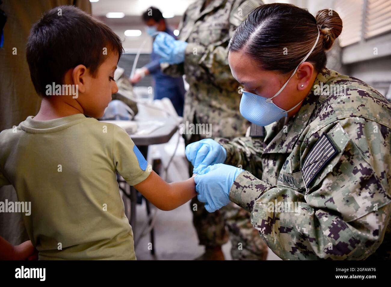 Un marin de la marine des États-Unis assiste un évacué afghan à bord de la base aérienne navale de Sigonella, le 22 août 2021. NAS Sigonella soutient actuellement la mission du ministère de la Défense pour faciliter le départ et la réinstallation en toute sécurité des citoyens américains, des bénéficiaires de visas d'immigration spéciaux et des populations afghanes vulnérables d'Afghanistan. Crédit : US Navy via CNP/MediaPunch Banque D'Images
