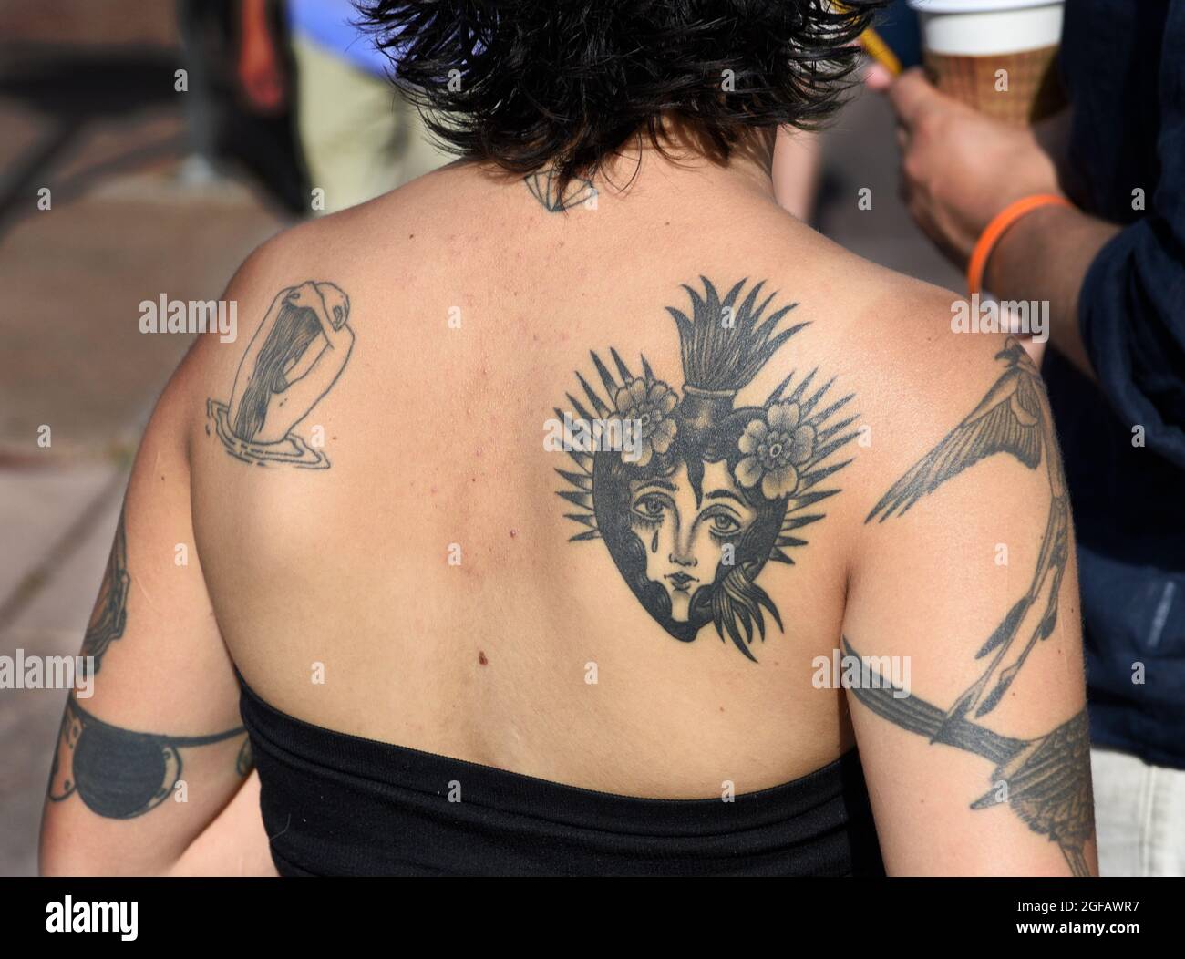 Une jeune femme avec un tatouage du Sacré-cœur sur son dos visite un spectacle d'art en plein air à Santa Fe, Nouveau-Mexique. Banque D'Images