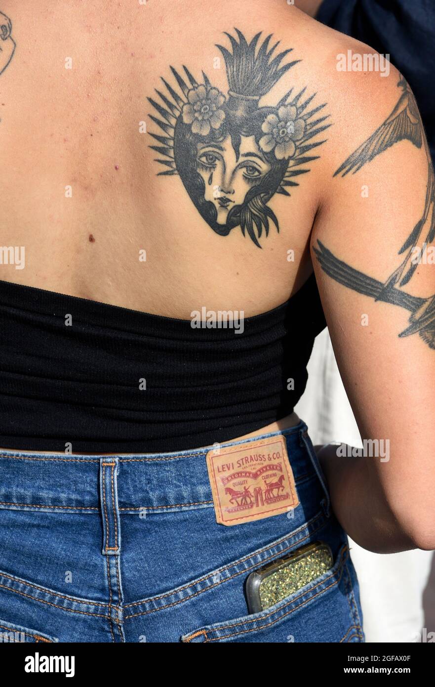 Une jeune femme avec un tatouage du Sacré-cœur sur son dos visite un spectacle d'art en plein air à Santa Fe, Nouveau-Mexique. Banque D'Images