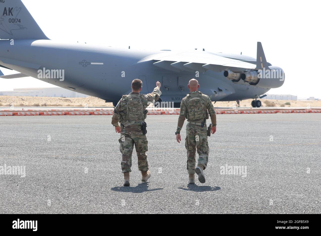 Deux aviateurs de la Force aérienne américaine affectés à la 386e Escadre expéditionnaire de la Force aérienne marchent vers le premier vol C-17 transportant des Afghans vers la sécurité au Koweït à la base aérienne Ali Al Salem, au Koweït. Bien que l'opération soit dirigée par le Département d'État, le ministère de la Défense a été chargé d'aider à fournir le transport, la sécurité, la logistique et le soutien médical aux détenteurs de visas d'immigration spéciaux à divers endroits, où ils devront suivre un processus rigoureux de paperasserie avant d'arriver à leur destination finale. À ce jour, le personnel du ministère de la Défense a aidé à apporter plus de Banque D'Images