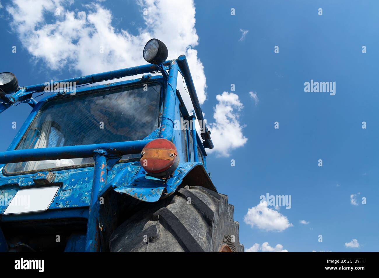 Vieux tracteur à roues bleues en ruine dans la cour arrière Banque D'Images