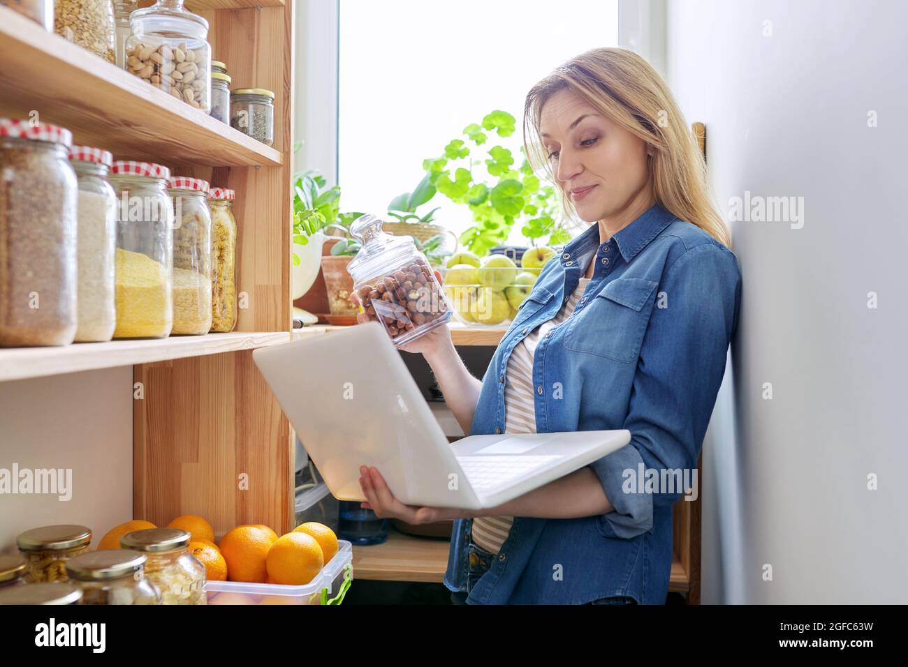 Femme en cellier avec bol de haricots blancs. Le meuble de rangement en  cuisine avec étagères en bois avec de la nourriture et des ustensiles Photo  Stock - Alamy