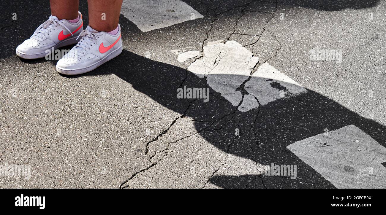 Logo Nike en rose sur les sneakers blanches d'une jeune femme sur asphalte  cassé avec des rayures blanches altérées à Braunschweig, Allemagne, 14 août  2021 Photo Stock - Alamy