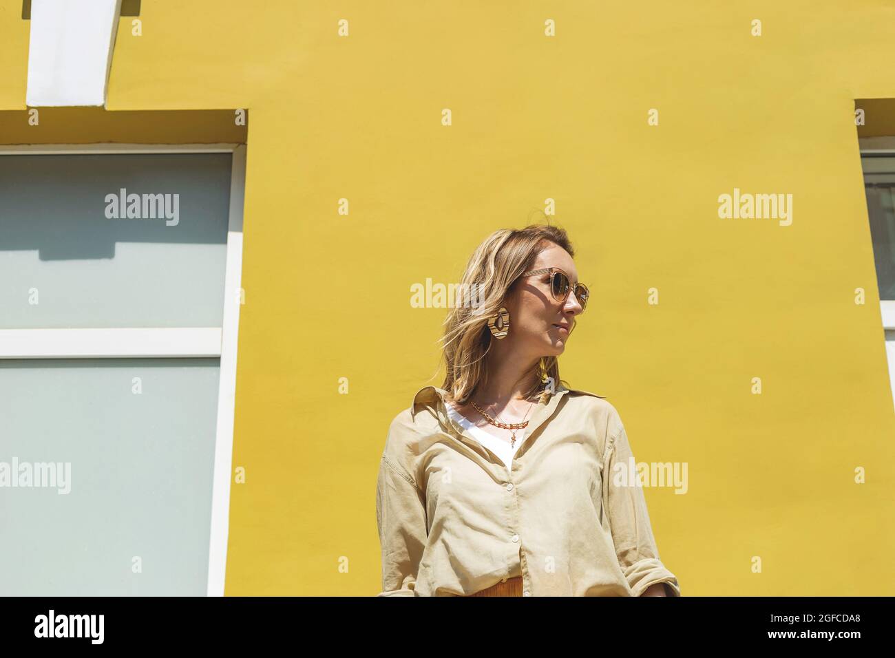 Femme élégante avec tenue jaune sur un mur aux couleurs vives Banque D'Images