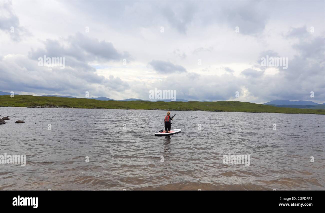 Une dame plus âgée s'agenouille sur Stand up Paddle Board, Loch Laidon, Perthshire Scottish Highlands, Royaume-Uni Banque D'Images