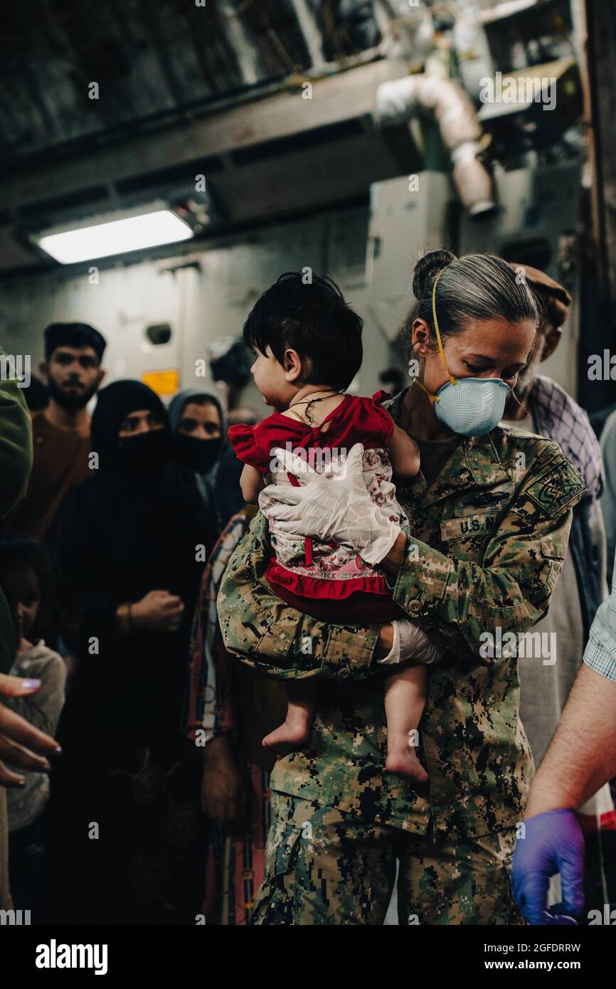 Le chef de commandement de la station aérienne navale de Sigonella, Anna Wood, transporte une personne évacuée en Afghanistan au large d'une force aérienne américaine C- 17 Globemaster lll à la station aérienne navale de Sigonella, le 22 août 2021. NAS Sigonella appuie actuellement la mission du ministère de la Défense visant à faciliter le départ et le déplacement en toute sécurité des citoyens américains, des bénéficiaires de visas d'immigration spéciaux et des populations afghanes vulnérables en provenance d'Afghanistan. L’emplacement stratégique de NAS Sigonella permet aux forces des États-Unis, des alliés et des pays partenaires de se déployer et d’intervenir au besoin pour assurer la sécurité et la stabilité en Europe, en Afrique et au Commandement central. (ÉTATS-UNIS Banque D'Images